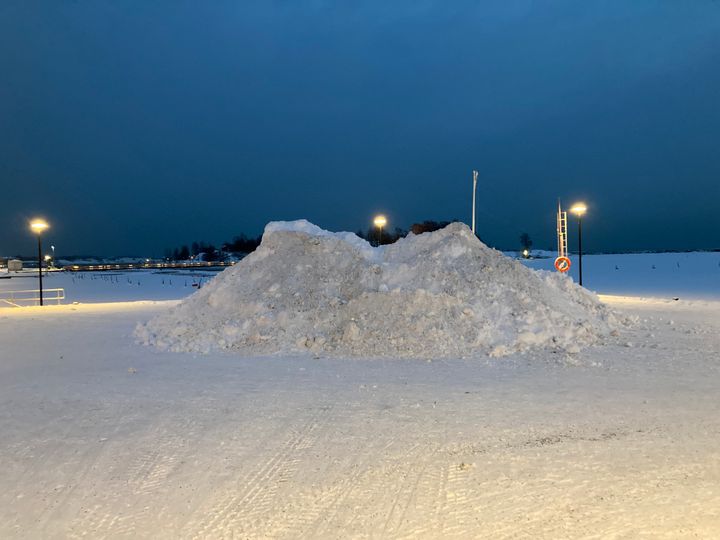Suuri lumikasa, jonka ympärillä on katulamppuja.