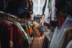 Opiskelija kurottaa kohti vaatteita vaaterekkien keskellä. Hänellä on yllään vaaleanpunainen alushame.