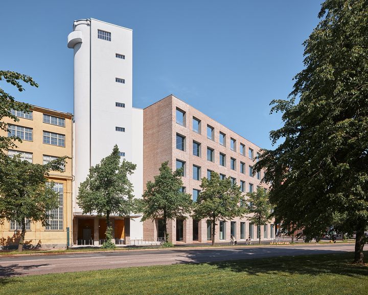 Taideyliopiston Sörnäisten kampus ja siihen kuuluva siilorakennus rannan puolelta kuvattuna.