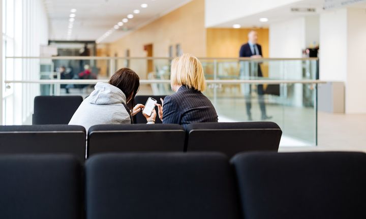 Två personer sitter nära varandra och tittar på samma telefon.