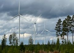 Neljä tuulivoimalaa tummaa taivasta vasten tuulisena syyspäivänä.