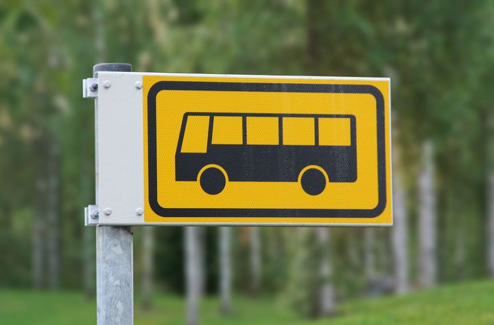Bussipysäkin liikennemerkki kesämaisemassa.