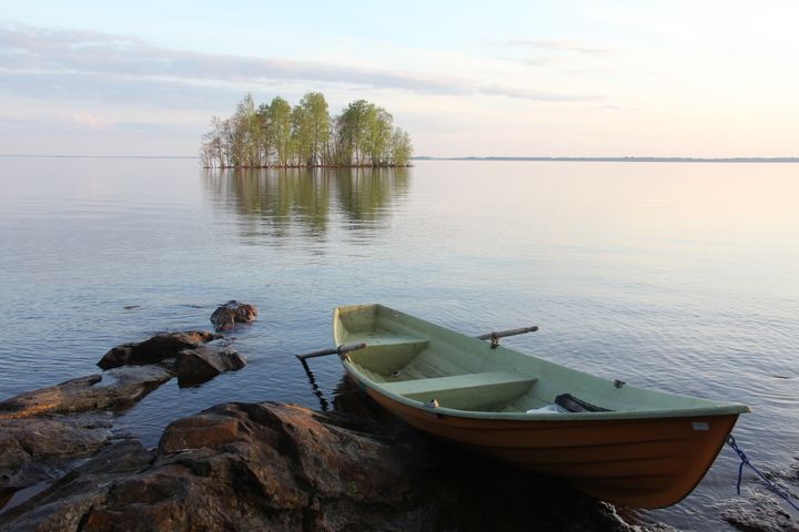 Kuva järvestä, saaresta ja veneestä.