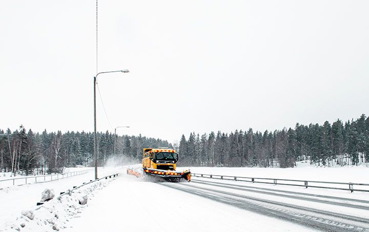 Keltainen lumiaura auraa lumista tietä.