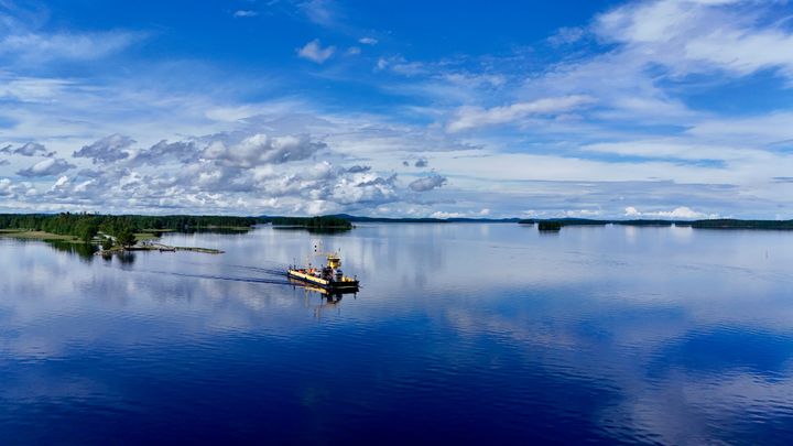 Keltainen lautta kulkee sinisellä järvellä.