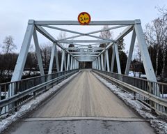 Silta, jonka yläpuolella on 3,4 metrin korkeusrajoitusmerkki. Lumisia puita ja taloja taustalla.