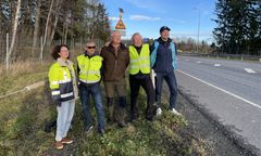 Viisi ihmistä seisoo tien reunalla, osalla heijastinliivit päällä.