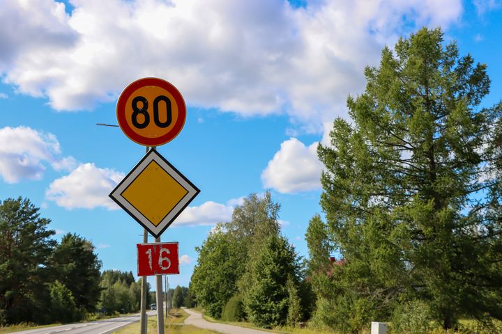 Tie, jossa on nopeusrajoitus 80 km/h, varoituskolmio ja numero 16 kyltti. Taustalla puita ja pilvinen taivas.