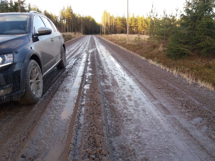Auto pysähtynyt mutaiselle hiekkatielle, jota reunustavat metsät.
