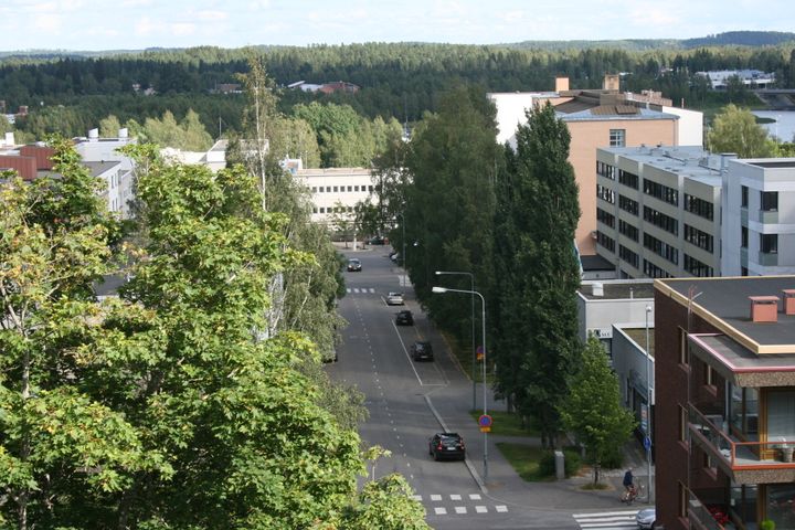 Rauhallinen katunäkymä ylhäältä. Matalahkoja kerrostaloja ja kourallinen henkilöautoja