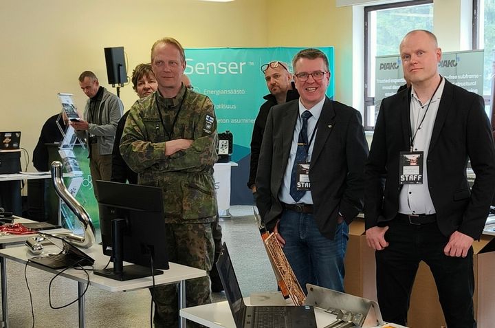 Kolme henkilöä Savo Defence minimessuilla.