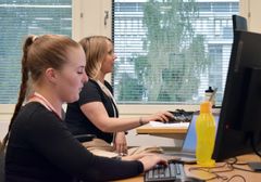 Kaksi henkilöä työskentelee tietokoneilla toimistossa.