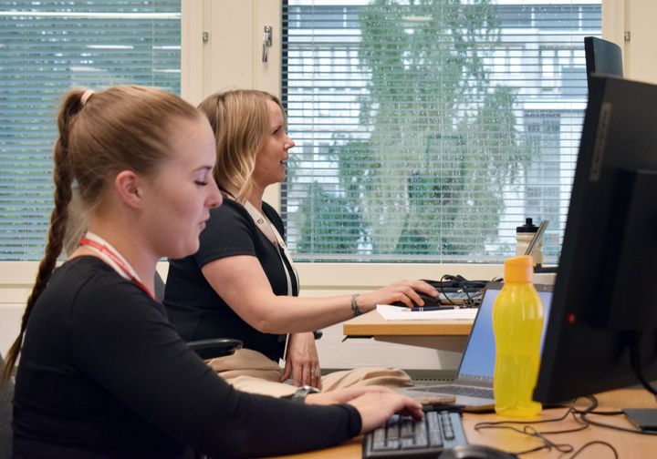 Kaksi henkilöä työskentelee tietokoneilla toimistossa.
