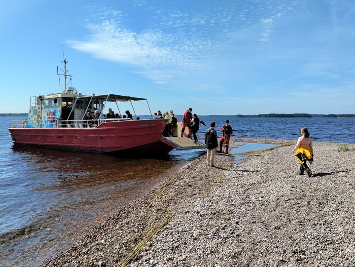 Ihmisiä nousemassa pyörälautalle rannalla.