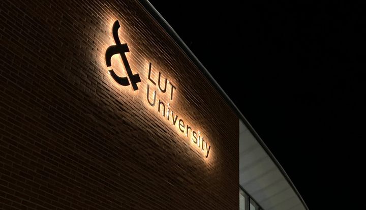 Logo LUT-yliopiston ulkoseinässä yöllä.
