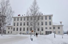Talvinen kuva kolmikerroksisesta vaaleasta rakennuksesta.