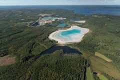 Ilmakuva Elementis Mineralsin Sotkamon tehdas- ja kaivosalueesta, etualalla näkyy laajoja vihreitä metsäalueita ja vaaleampi rikastushiekka-allas, taustalla järvi ja sininen taivas.