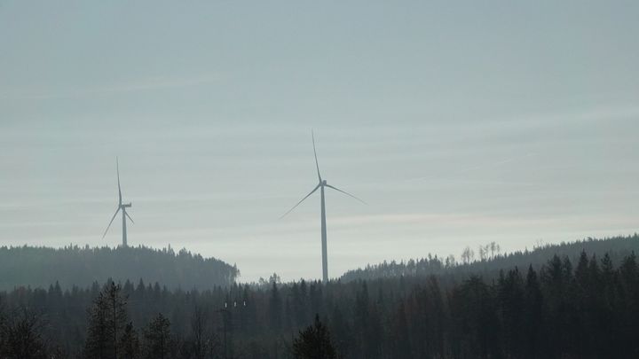 Kaksi tuulivoimalaa metsäisessä maisemassa.