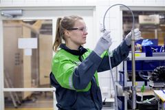 Henkilö työskentelee teollisuusympäristössä suojalasit ja -käsineet yllään.