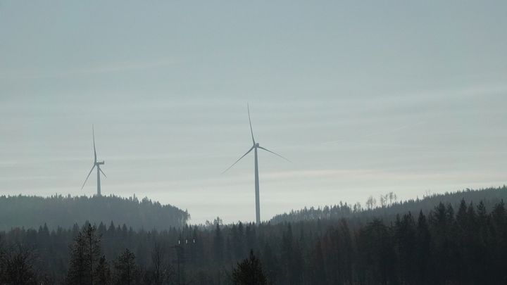 Kaksi tuulivoimalaa metsäisessä maisemassa.