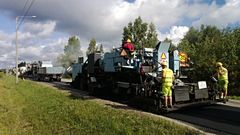 Asfalttikone ja työntekijöitä tietyömaalla.