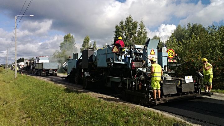 Asfalttikone ja työntekijöitä tietyömaalla.