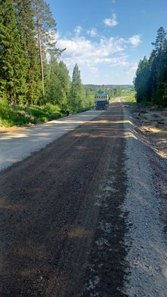 Tieosuus korjauksen alla, kaukana näkyy kuorma-auto. Tien ympärillä on metsää.