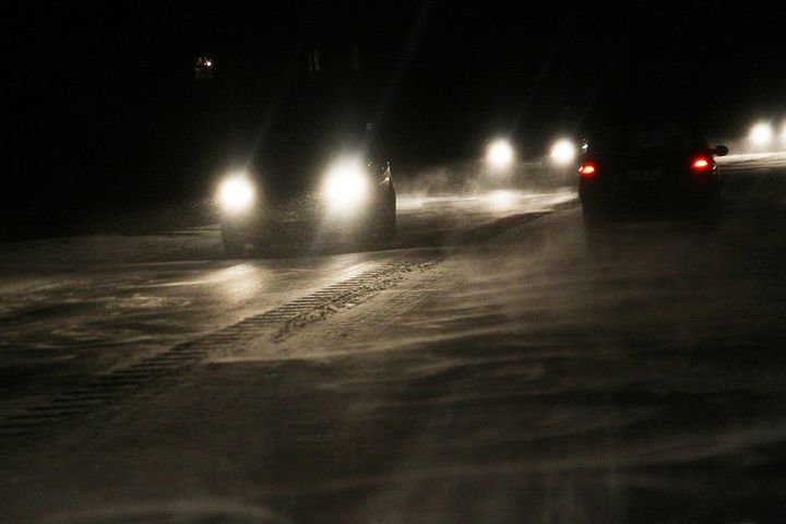 Autot ajavat pimeässä liukkaalla tiellä.