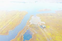 Ilmakuva kaivinkoneesta työstämässä vesistöä ja rantoja sumuisella suolla.