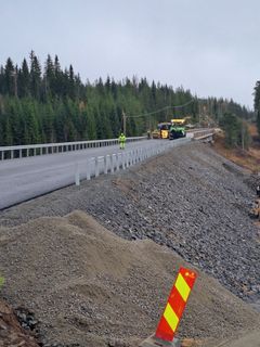 Asfalttikone työskentelee uudella tieosuudella, molemmin puolin metsämaisema.