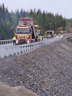 Rakennustyömaa maantiellä, useita ajoneuvoja ja työmiehiä työskentelemässä.