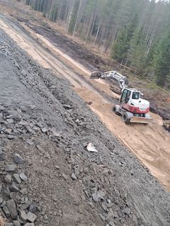 Maanrakennustyömaa metsäisellä alueella, kaivinkoneita töissä.