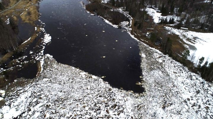 Osittain sula joki kuvattuna yläpuolelta, joen alaosassa pakkautunutta jäätä.