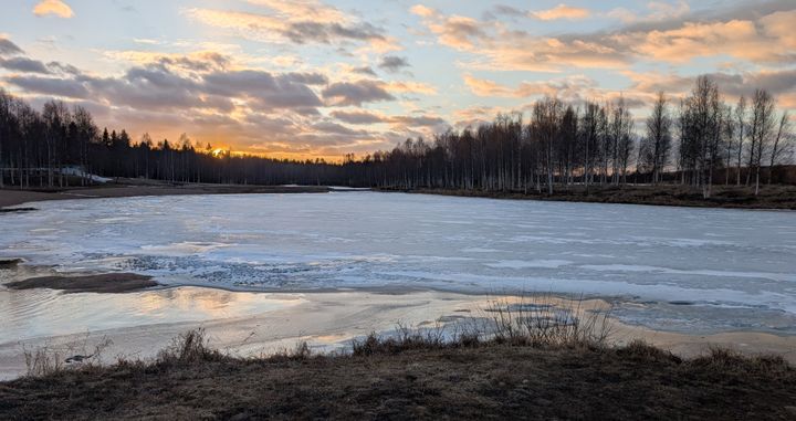 Puolittain jäässä oleva uimaranta, auringonlasku ja puolipilvinen sää.