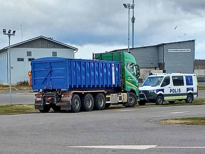 Jätekuljetusajoneuvo, jonka edessä pysäköityneenä Poliisi-auto.