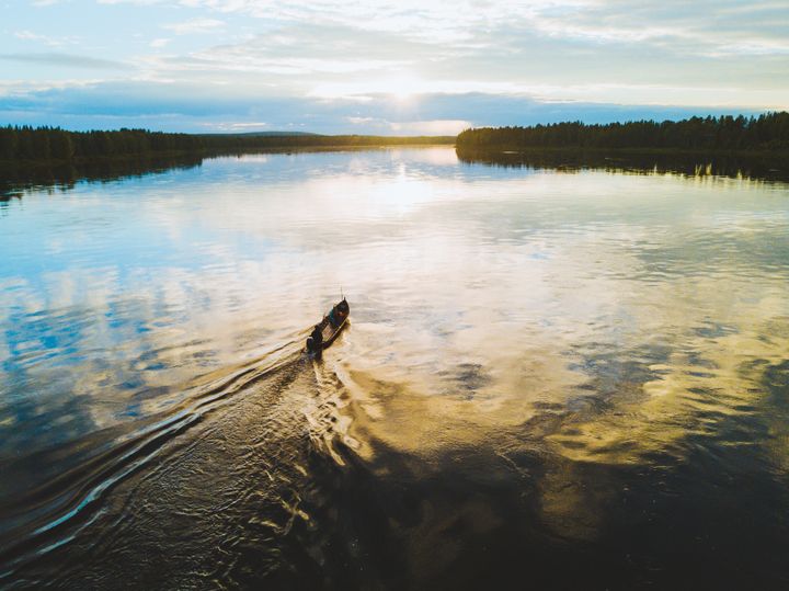 Kuvassa kalastajien vene, joka ajaa jokea pitkin.