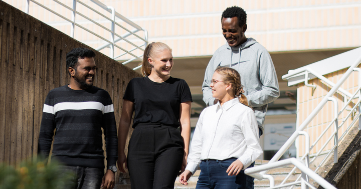 Fyra vuxna, två kvinnor och två män, kommer glatt nerför trappan. Männen har invandrarbakgrund, kvinnorna är infödda finländare.