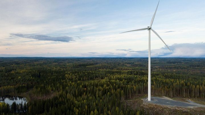 Tuulivoimala ja sille johtava tie ilmasta kuvattuna, taustalla lampia ja metsää.