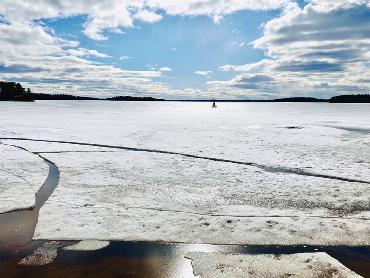 Polkupyörä kaukaisuudessa sulavalla järvenjäällä.
