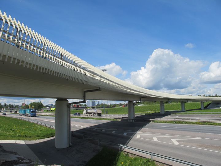 Silta kulkee tien yli, sininen taivas taustalla.