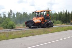 Asfalttikone päällystää pyörätietä Loviisassa, taustalla metsää.
