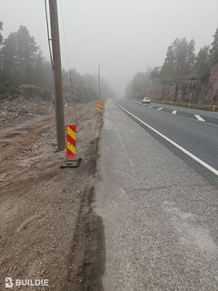 Sumuinen tie, jolla on kaide ja tieviittoja. Taustalla näkyy metsää ja kallioita.