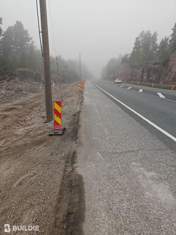 Sumuinen tie, jolla on kaide ja tieviittoja. Taustalla näkyy metsää ja kallioita.