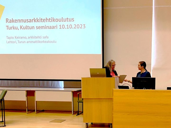 Ylitarkastaja Kirsti Virkki ojensi palkinnon kaupunginarkkitehti Leena Arvela-Hellenille 10.10.2023 Korjaamisen jalo taito -seminaarissa.