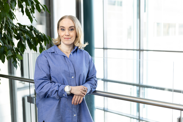 Vuoden sosiaalialan asiantuntija Anna Pekkarinen seisoo kuvassa kaiteen vieressä. Taustalla suuri ikkuna.