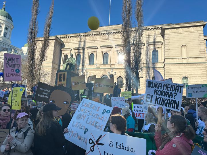 Yleisö osoittamassa mieltä kylttien kanssa Suomen Pankin edessä.