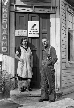 Det planerade byggandet av Brunakärr väcker oro bland dess invånare. Skoflickaren August Johansson med maka och katt utanför sitt hem i Brunakärr, Helsingfors augusti 1938.