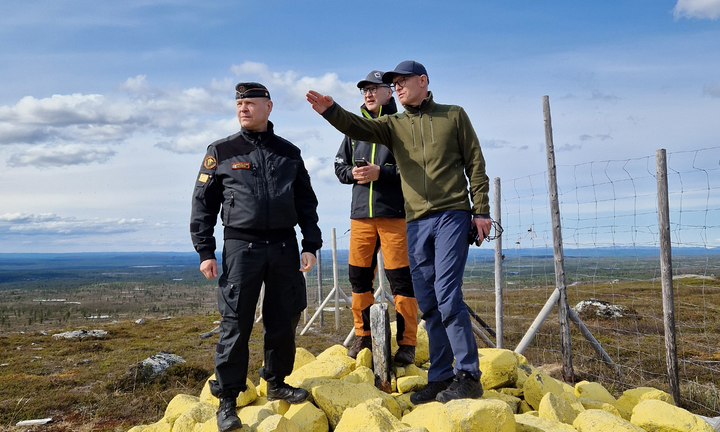 Kolme miestä tarkastamassa rajapyykkiä nro 353 vuoristoisella alueella.