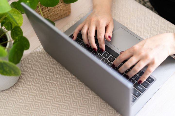 Kädet kannettavan tietokoneen näppäimistöllä.