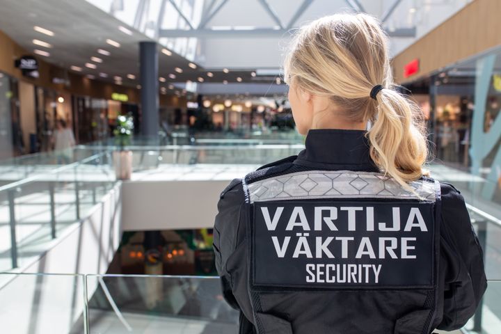 Kuvassa vartija, joka katsoo kauppakeskusta.